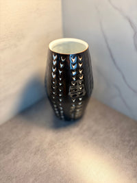 Top-down view of a handmade black glazed ceramic vase showing the white interior rim and carved geometric chevron surface pattern