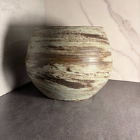 Wheel-thrown round ceramic form with horizontal iron-oxide streaks over pale mint glaze, full front view